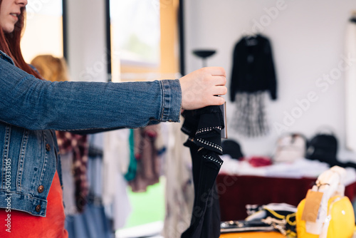 close-up of a young woman's hands, choosing a T-shirt to buy, in a fashion shop. shopping concept.