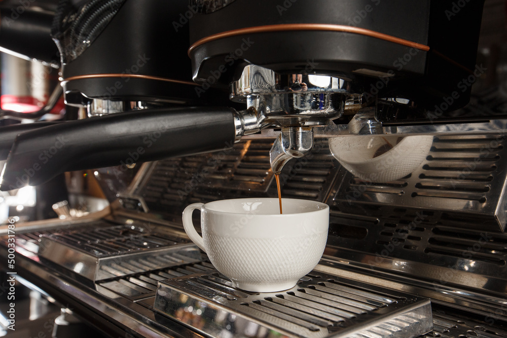 Pouring coffee stream from professional machine in cup. Barista making espresso, using filter holder. Flowing fresh ground coffee. Pouring coffee stream from professional machine in cup. Barista making espresso, using filter holder. Flowing fresh ground coffee.