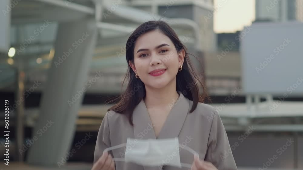 A portrait of Businesswoman is taking face mask off in modern City , people lifestyle , End of Covid-19 pandemic concept A portrait of Businesswoman is taking face mask off in modern City , people lifestyle , End of Covid-19 pandemic concept