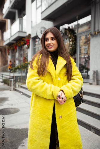 Young pretty girl with long hair in yellow fur coat. Fur and fashion concept. Beautiful people.