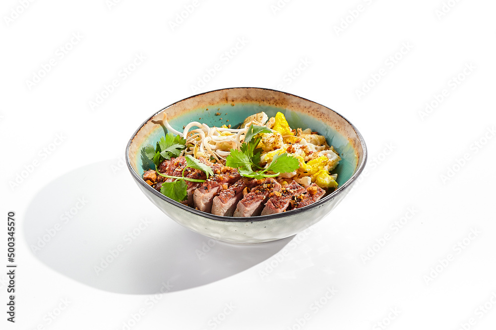 Pan asian traditional dish - fried rice with vegetables, shredded omelette and duck. Oriental wok with rice on white background. Nasi goreng with duck on isolated background with shadows.