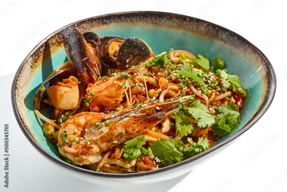 Japanese soba with seafood cooked on wok in asian style on white background. Noodle seafood in ceramic bowl. Indonesian wok with prawn, mussels and soba noodles. Spicy thai dish with shrimp and udon.