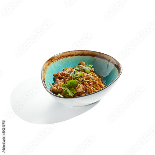 Japanese soba with chicken cooked on wok in asian style on white background. Noodle with chicken in ceramic bowl. Indonesian wok with soba noodles. Spicy thai dish with meat and udon.