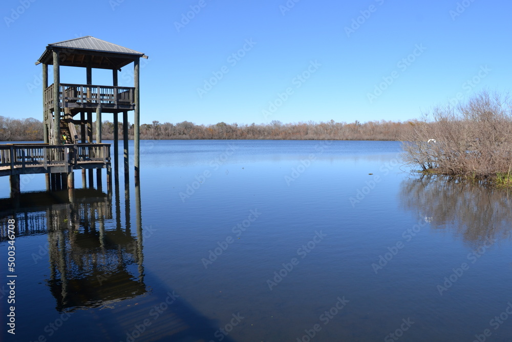 Calm water surface of White Lake and wooden tower for bird watching, Cullinan Park, Sugar Land, Texas