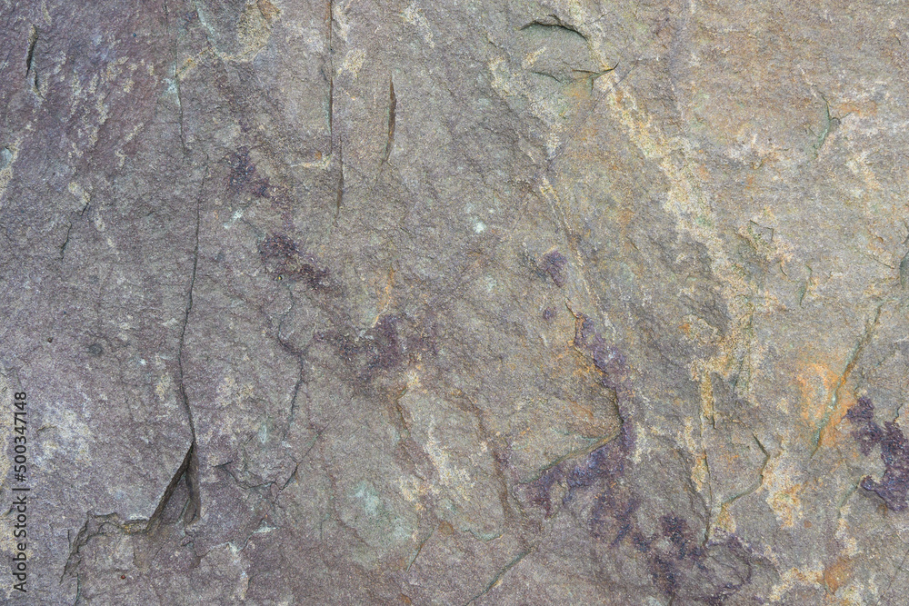 Naklejka premium Rough cut rock in dark colors of gray and purple, as a natural background 