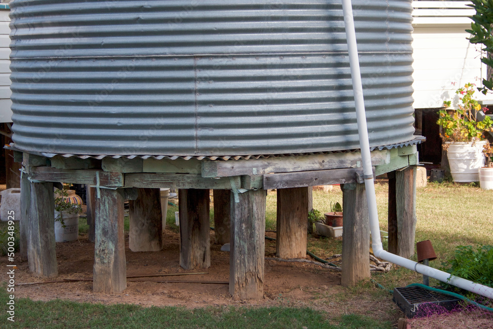 Old Corrugated Iron Water Tank in Yard with Wooden Stumps Stock Photo