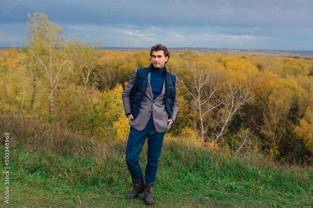 Tall handsome man outdoor in autumn forest on the hill