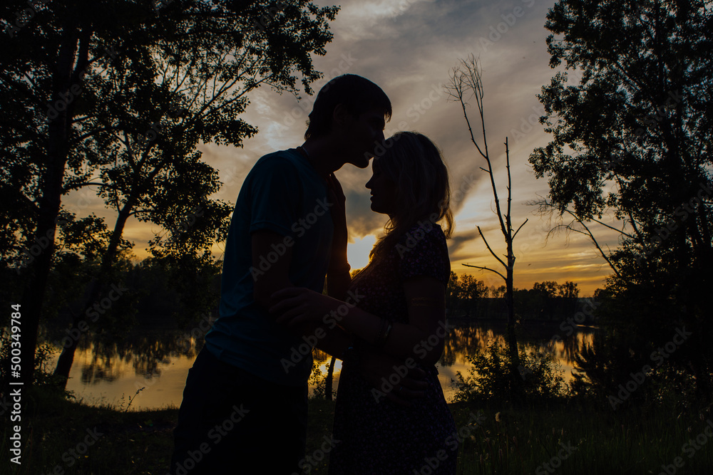 The silhouette of a young couple loving each other on the background of the sunset.