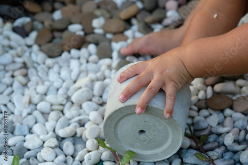 toddle hands play rocks and pot