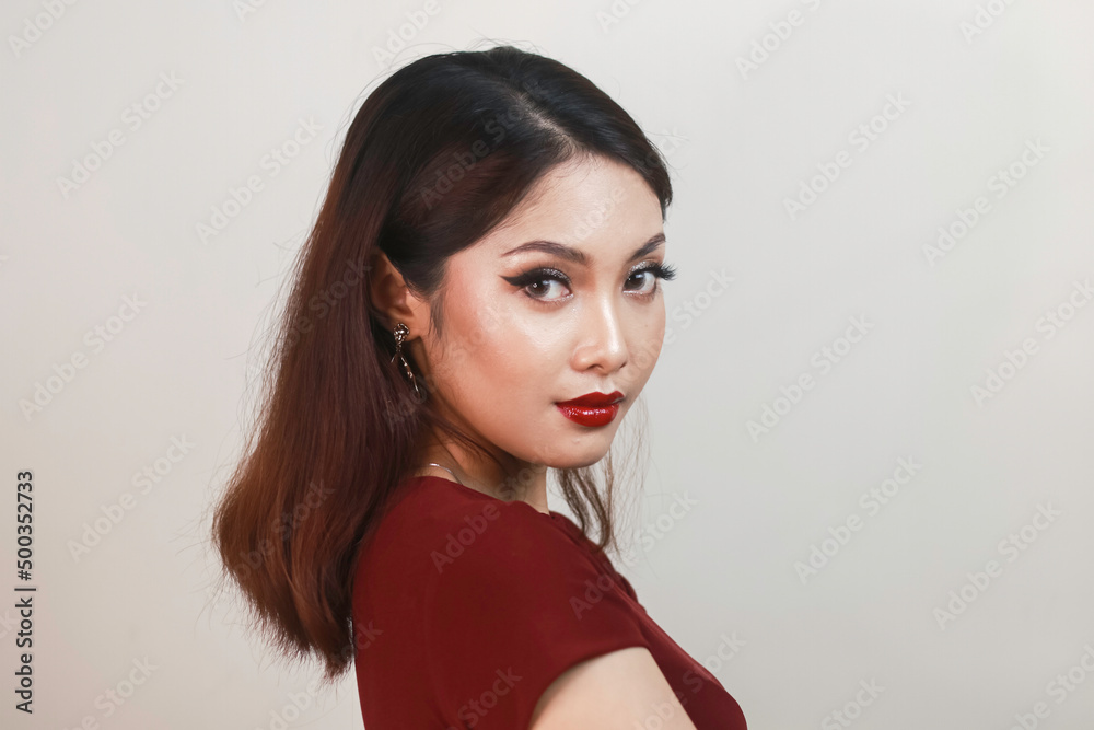 Naklejka premium A fierce-looking Asian woman in a red shirt side posing in front of white background