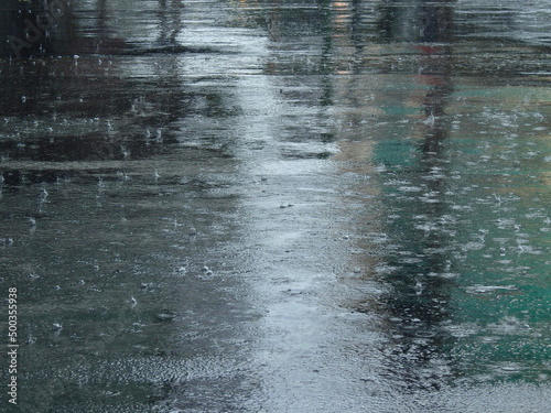 raindrops falling on wet asphalt road with reflection