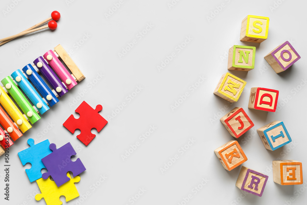 Wooden cubes with letters, xylophone and puzzle pieces on light background Wooden cubes with letters, xylophone and puzzle pieces on light background