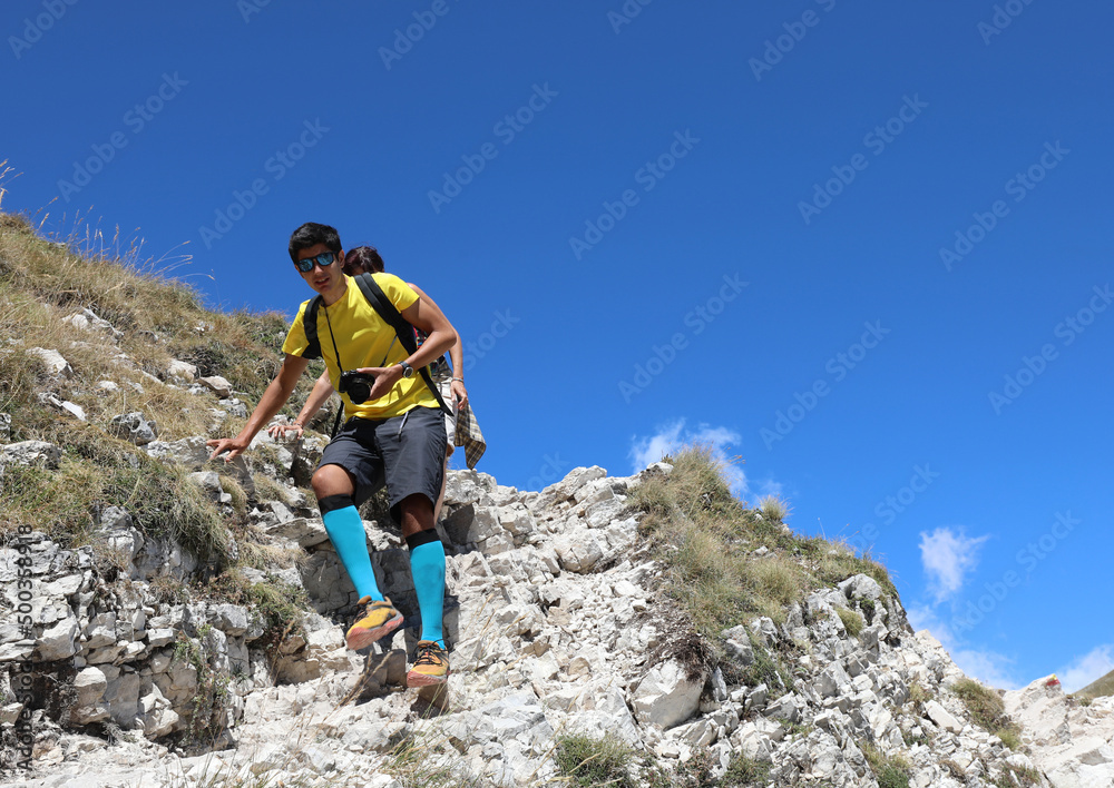 boy with goggles and camera on a rugged mountain path in summer while hiking