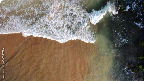 waves breaking at black rocks in Geriba Beach in Buzios, Brazil, Aerial top down view photo