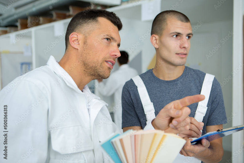 painter with apprentice looking at colour samples painter with apprentice looking at colour samples