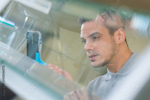 reflected view of man cleaning glass louver window