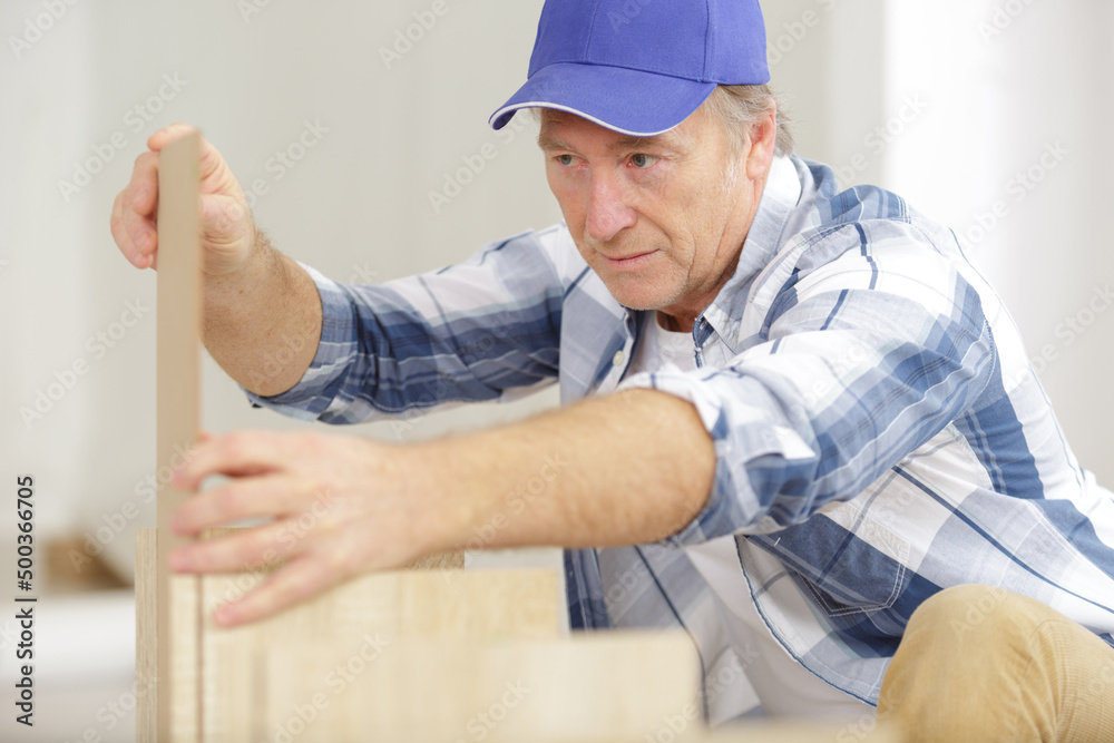 mature man assembling furniture in new home mature man assembling furniture in new home