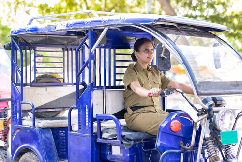 Foto Portrait of happy woman in uniform driving six seater electric rickshaw