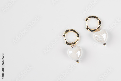 Women's gold earrings with pendants in the shape of a heart. Women's jewelry isolated on white
