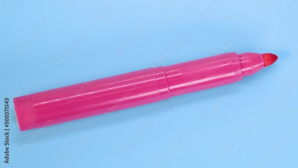 Pink marker pen rotating on blue surface background, macro shot close up view detail. Pink marker pen rotating on blue surface background, macro shot close up view detail.