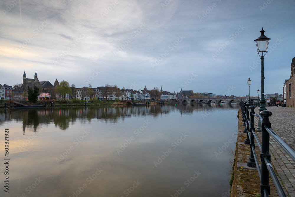 Long exposure view of the historic skyline of Maastricht with a view over the river Meuse and the old roman bridge with on the side the typical street lights of the inner city.