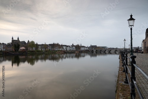 Long exposure view of the historic skyline of Maastricht with a view over the river Meuse and the old roman bridge with on the side the typical street lights of the inner city.