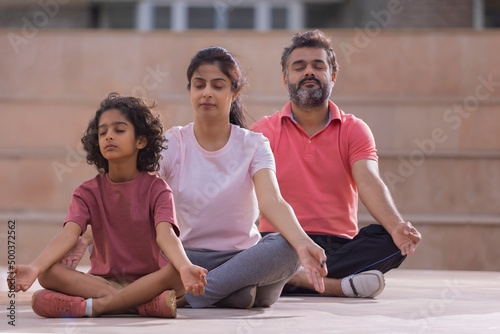 Portrait of happy family meditating together at outdoor in the morning