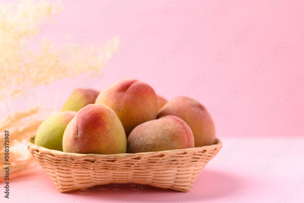 Peach fruit in basket on pink background Peach fruit in basket on pink background