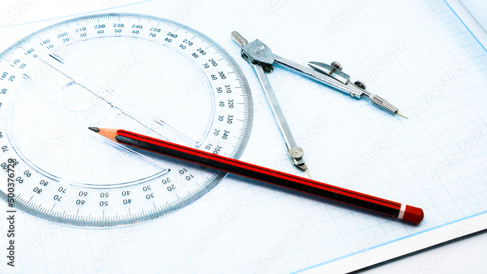 On blue graph paper are compasses, protractor, ruler, and a pencil