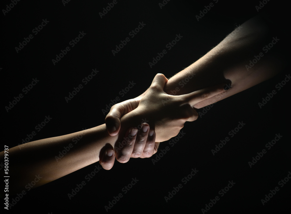 Two trength ands. Helping hand to a friend. Rescue or helping gesture of hands. Concept of salvation. Hands of two power people at the time of rescue, help. Isolated on black background.
