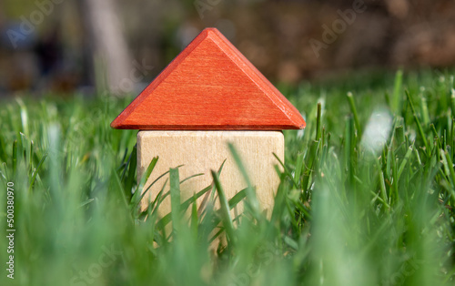 toy house from eco wooden cubes on green grass. red roof. Mortgage property insurance, personal own home concept. copy space. buy house, insurance and mortgage, buying or rent, construction.
