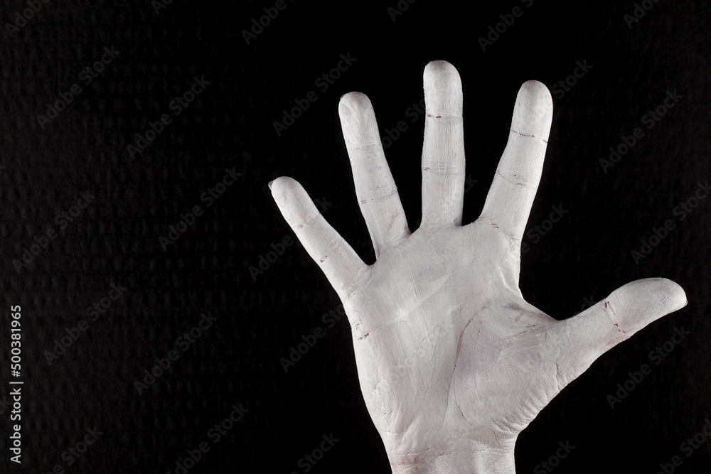 The inside of the hand with the fingers spread apart. The gesture, the body, the tension. The hand has been painted white. Black color in the background.