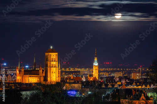 A full moon rising over the city of Gdansk at night. Poland