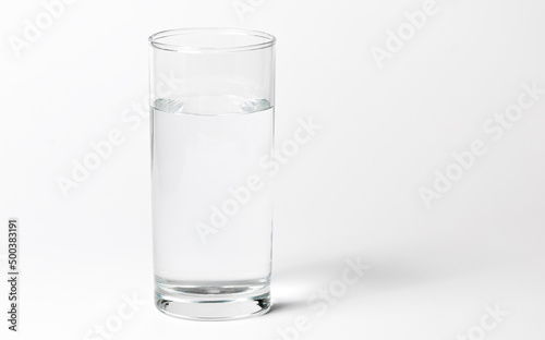 A clean glass transparent glass with water on a white background with a shadow. Side view and a little from above
