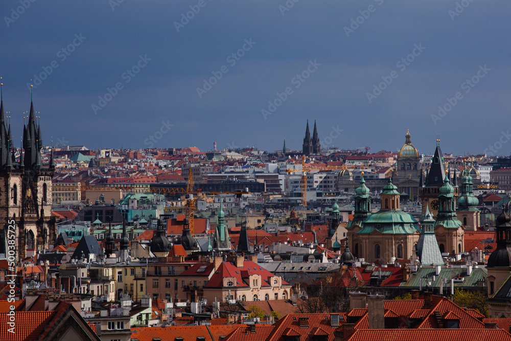 Skyline of Prague in the sun. the red roofs of the historic city center of Prague. Many steeples, towers dominate the city. Construction cranes stand out in the city center.