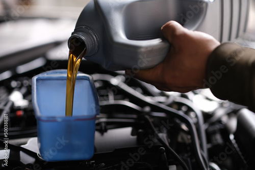 Auto mechanic pours car oil for replacement in engine