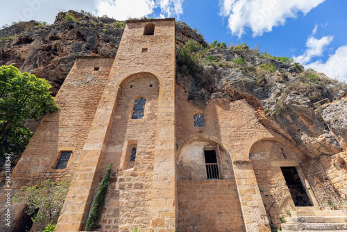 Fotografia Historic antique Saint-Cristofol troglodyte church and bell tower linked to solid rock in medieval Peyre village