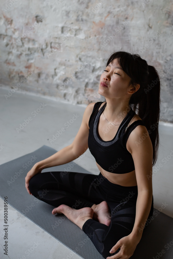 cute Asian girl with dark long hair in workout sportswear resting after a workout cute Asian girl with dark long hair in workout sportswear resting after a workout
