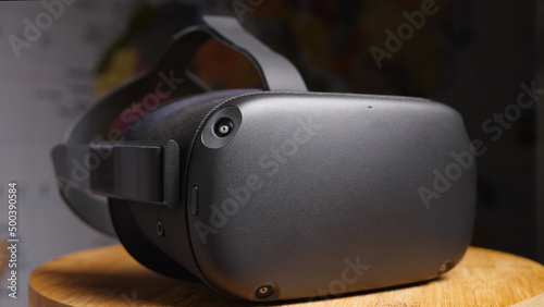 Black virtual reality glasses with four cameras on a wooden board against a world map. VR helmet close-up.