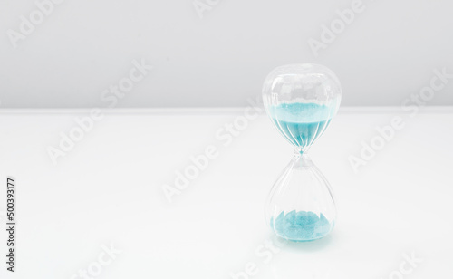 Hourglass on bright light, sandglass with blue sand