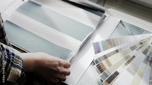 Woman fliping through catalog with roller blinds or window shade. Duo window roller system day and night. Choice of roller blinds.