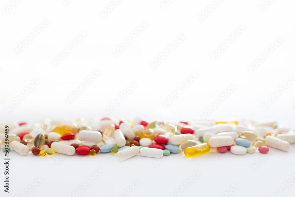 Lekarstwa i witaminy w tabletkach rozsypane na białym tle, suplementacja diety, leczenie przewlekłe, farmacja - obrazy, fototapety, plakaty 