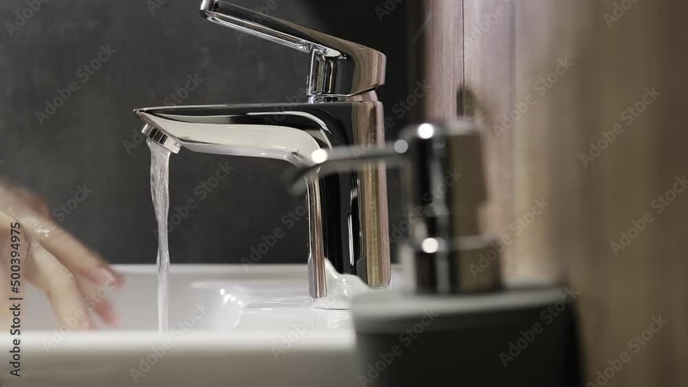 Woman pushes the dispenser and the liquid soap is squeezed in her hand. Woman washing her hands in the bathroom using a mild gel for advanced skin care and disinfection. Woman pushes the dispenser and the liquid soap is squeezed in her hand. Woman washing her hands in the bathroom using a mild gel for advanced skin care and disinfection.