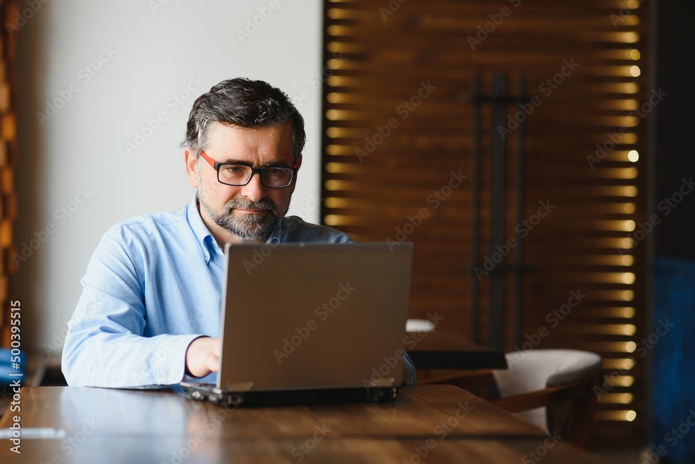 Business, technology and people concept , senior businessman with laptop computer drinking coffee at modern cafe. Business, technology and people concept , senior businessman with laptop computer drinking coffee at modern cafe.