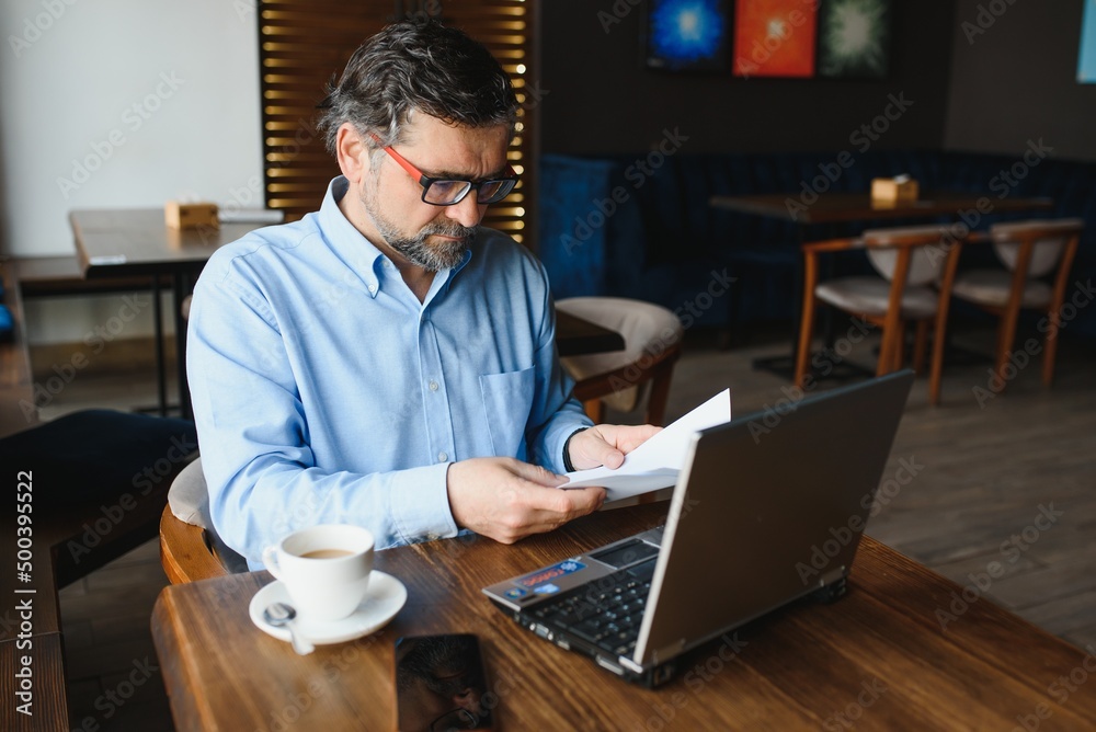Business, technology and people concept , senior businessman with laptop computer drinking coffee at modern cafe.