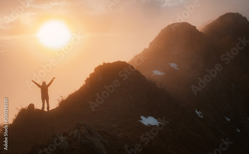 female tourist with a backpack in autumn on the mountain with outstretched arms welcomes admires the sunset