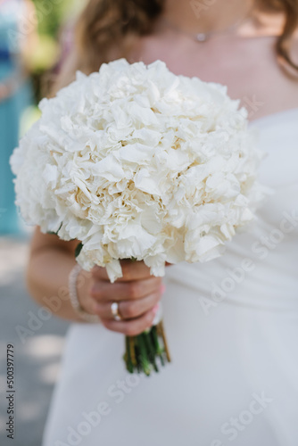 The bride holds a beautiful bouquet of white flowers. Close-up view