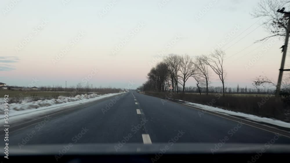 Driving on a highway with black asphalt and white lines on a cloudy day, the road goes into the distance through the fields to the horizon
Driving on a highway with black asphalt and white lines on a cloudy day, the road goes into the distance through the fields to the horizon