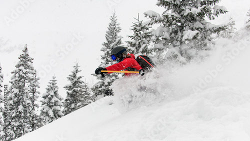 Close-up view of skier riding down on snow-covered slope and splash of snow around him