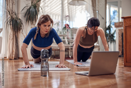 Pretty women working out at home. Adult ladies with beautiful shaped bodies exercising in the apartment.